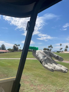 Large metallic hand sculpture on a grassy field with a blue sky.